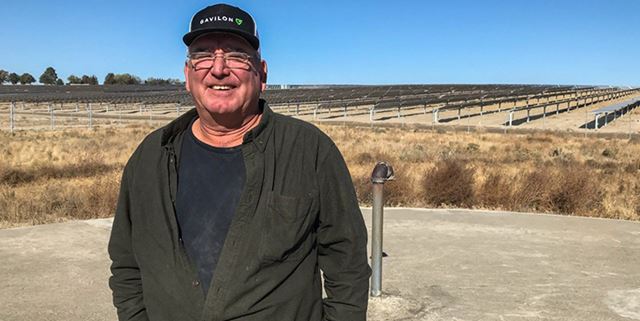 Man smiling in front of solar farm