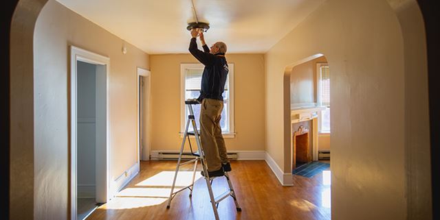 Person changing light bulb on ladder