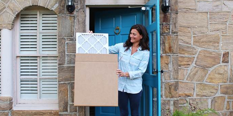 Woman holding furnace filter at door