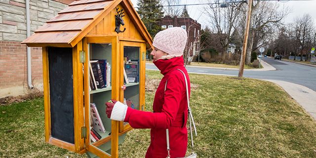 Woman looking at book from a sidewalk library