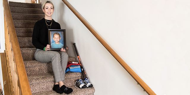 Woman sitting on stairs holding son's picture