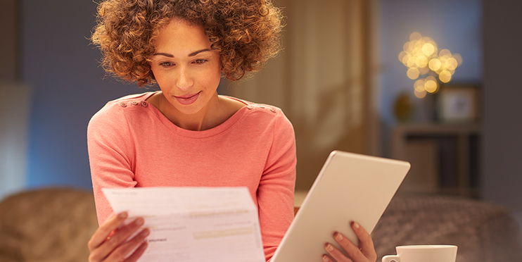 Woman looking at paper and tablet