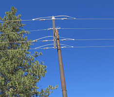 A fire-resistant steel pole stands tall in front of a blue sky.