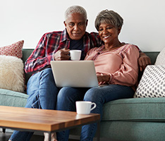 Man and woman looking at laptop together on couch