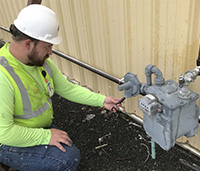 Man in hard hat checking natural gas meter