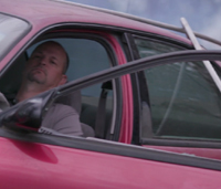 Man sitting in car with fallen power line on roof