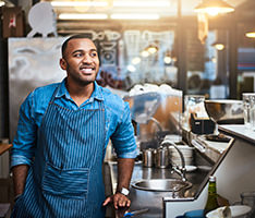 Man in an apron working at a coffee shop smiles