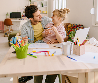 Father and daughter coloring together in front of a laptop
