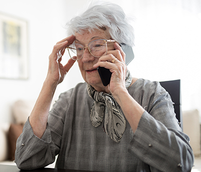 Senior woman talking on the phone, her hand is resting on her head and she is looking slightly concerned.