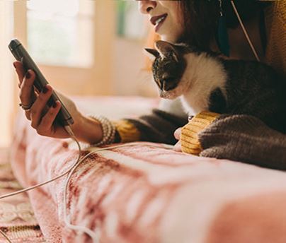 Woman looking at phone while snuggling with pet cat