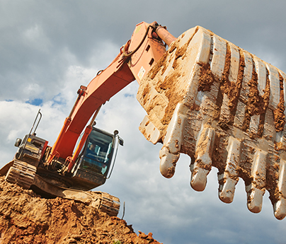 Large excavator on a pile of dirt outside.