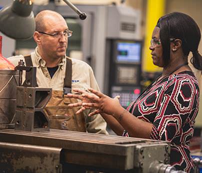 Man and woman wearing safety glasses talking in workshop