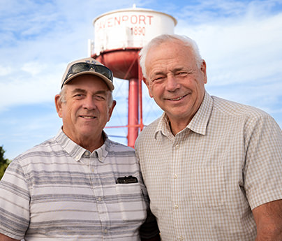 Two older men smiling in front of Davenport water tower