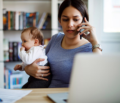 Concerned woman on the phone holding a baby looking at laptop