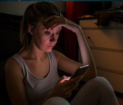 Frustrated looking woman in the dark looking at phone