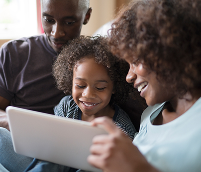 Mother and father look at tablet with younger daughter.