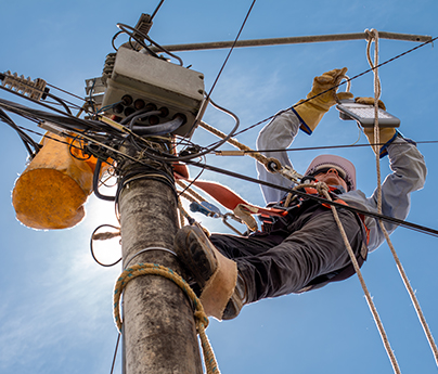 Lineman works on a power line on a sunny, blue sky day.