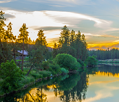 Golden sunset over a river with trees and a house