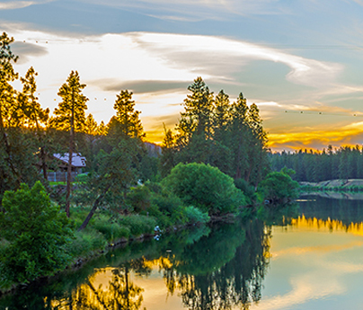 Golden sunset over a river with trees and a house